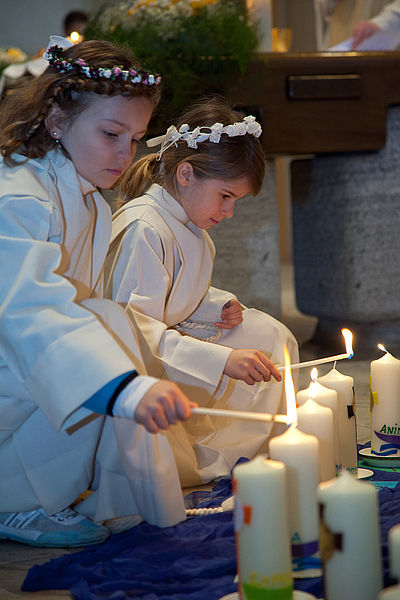Kinder, die Kerzen in einer Kirche anzünden